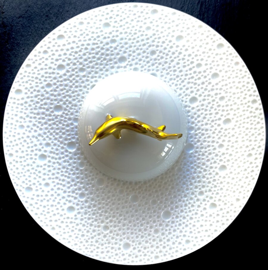 White relief plate with a golden dolphin